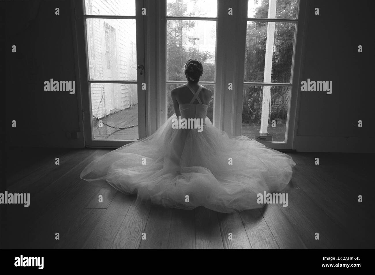 Giovane donna che guarda fuori della finestra mentre vestita come una sposa. Foto Stock