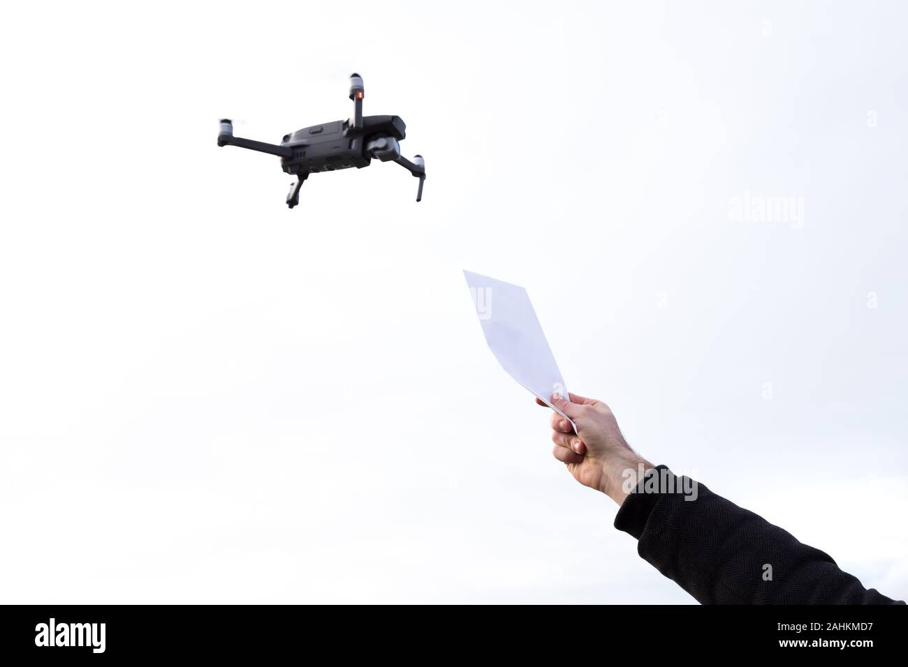 Un drone autonomo per la consegna della posta con una mano che tiene un pacchetto al cielo. Foto Stock