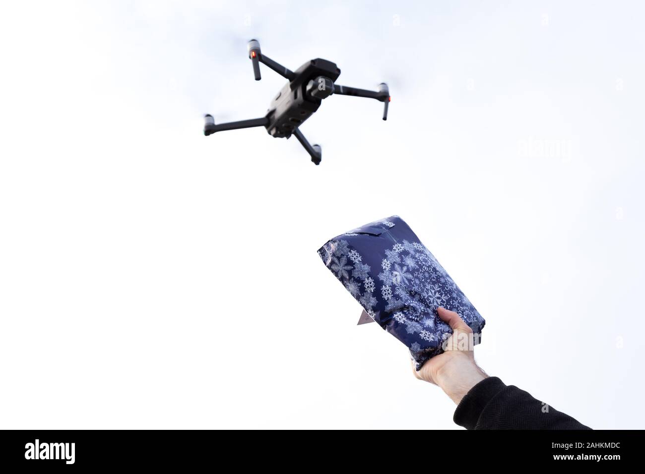 Un drone autonomo per la consegna della posta con una mano che tiene un pacchetto al cielo. Foto Stock