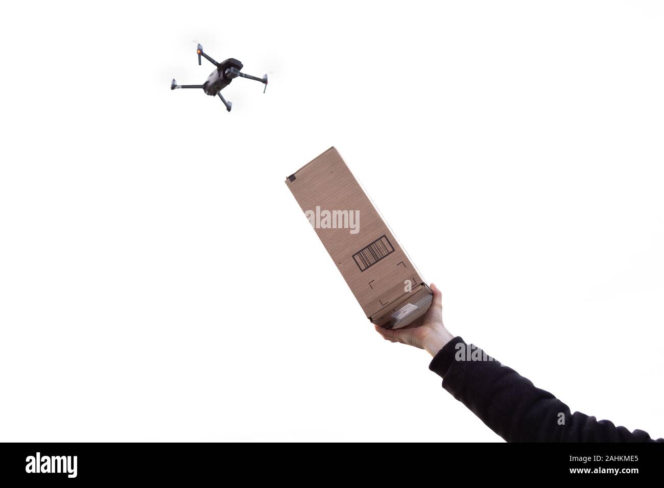Un drone autonomo per la consegna della posta con una mano che tiene un pacchetto al cielo. Foto Stock
