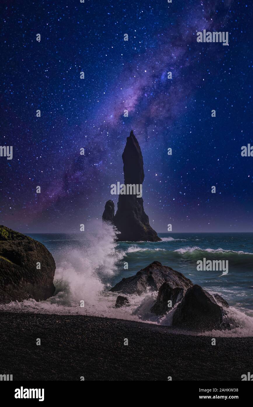 Una spiaggia di sabbia nera con formazioni rocciose e surf di notte nei pressi di Vik, Islanda, l'Europa. Foto Stock