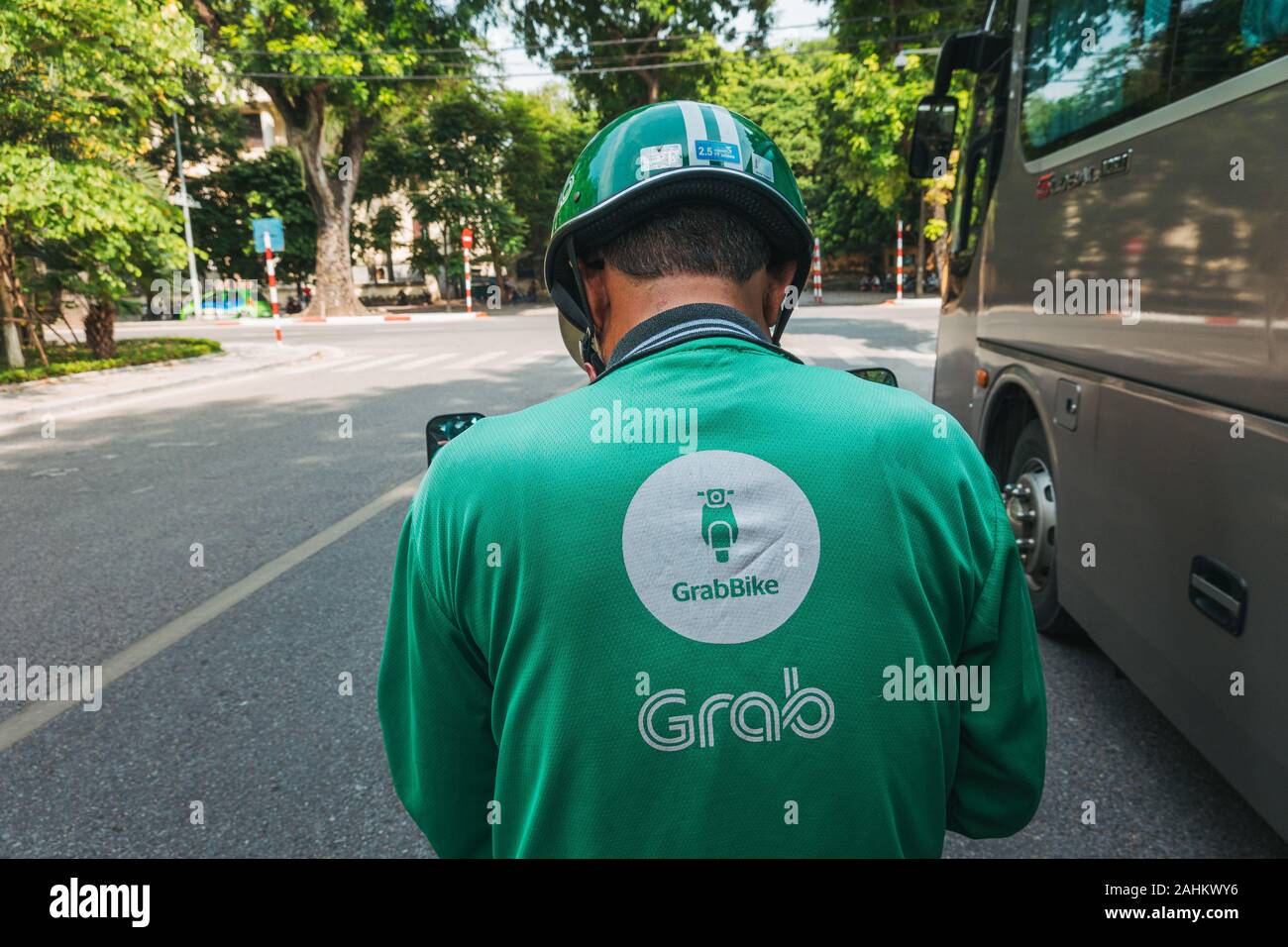 Un Grab Bike Rider controlla il loro telefono in attesa del processo successivo ad Hanoi, Vietnam. Grab è il Sud Est Asiatico più popolare ride salutando e app per la consegna Foto Stock