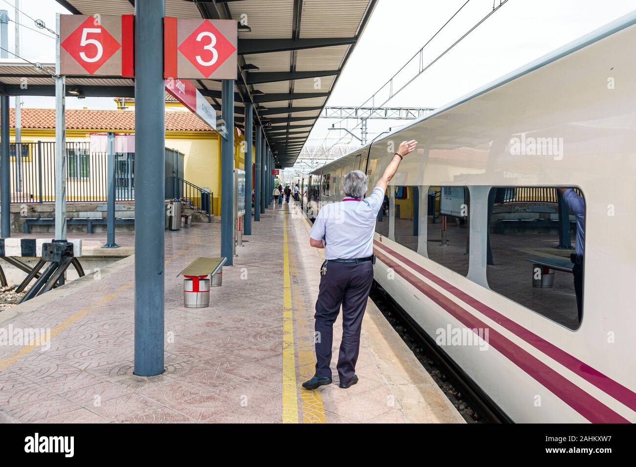 Spagna,Sagunt,stazione ferroviaria Renfe,piattaforma,conduttore,fermata,equipaggio,lavoro,segnalazione ondulazione,braccio sollevato,uomo,ispanico,ES190827028 Foto Stock