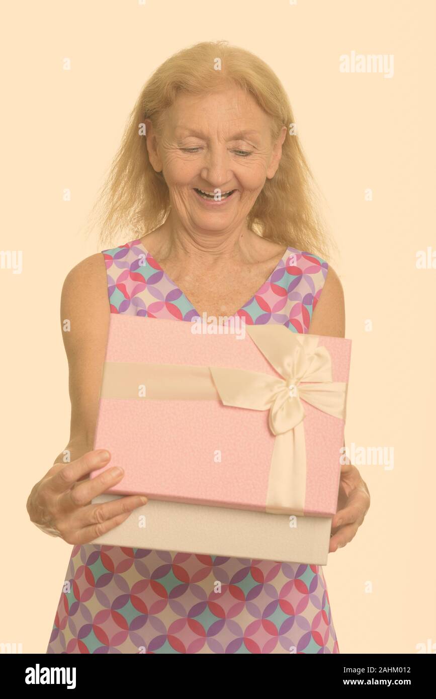 Studio shot di felice senior donna sorridente durante l'apertura della confezione regalo Foto Stock