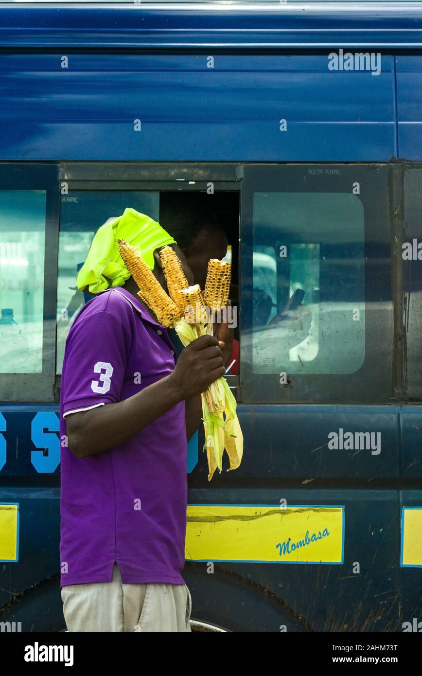 Un uomo keniano vendita di mais abbrustolito ai passeggeri in un bus di matatu, Kenya, Africa orientale Foto Stock