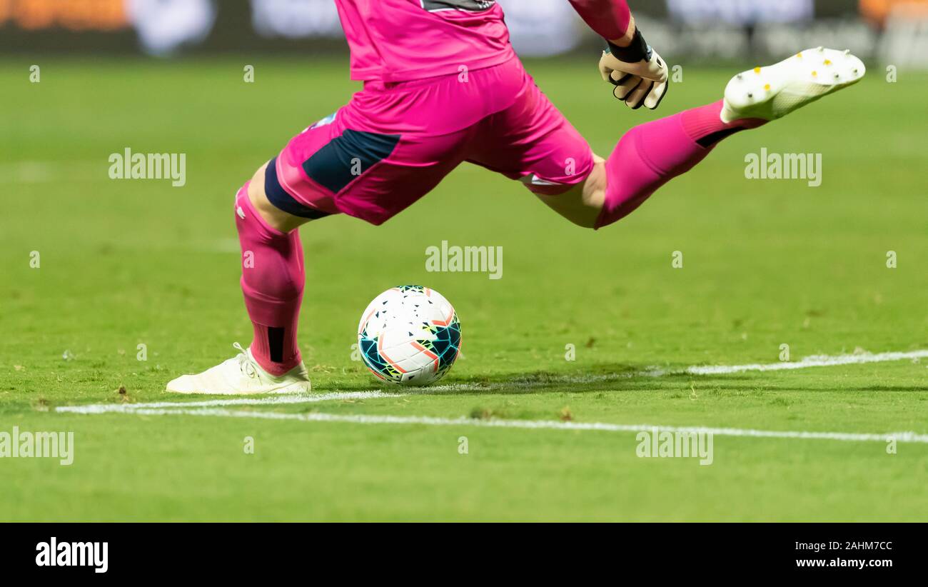 Un giocatore che sta per dare un calcio a un bianco pallone da calcio su un prato verde campo sportivo Foto Stock