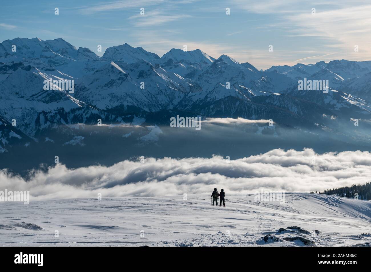 Coppia di escursionisti con racchette da neve davanti a un mare di nebbia e le alpi svizzere Foto Stock