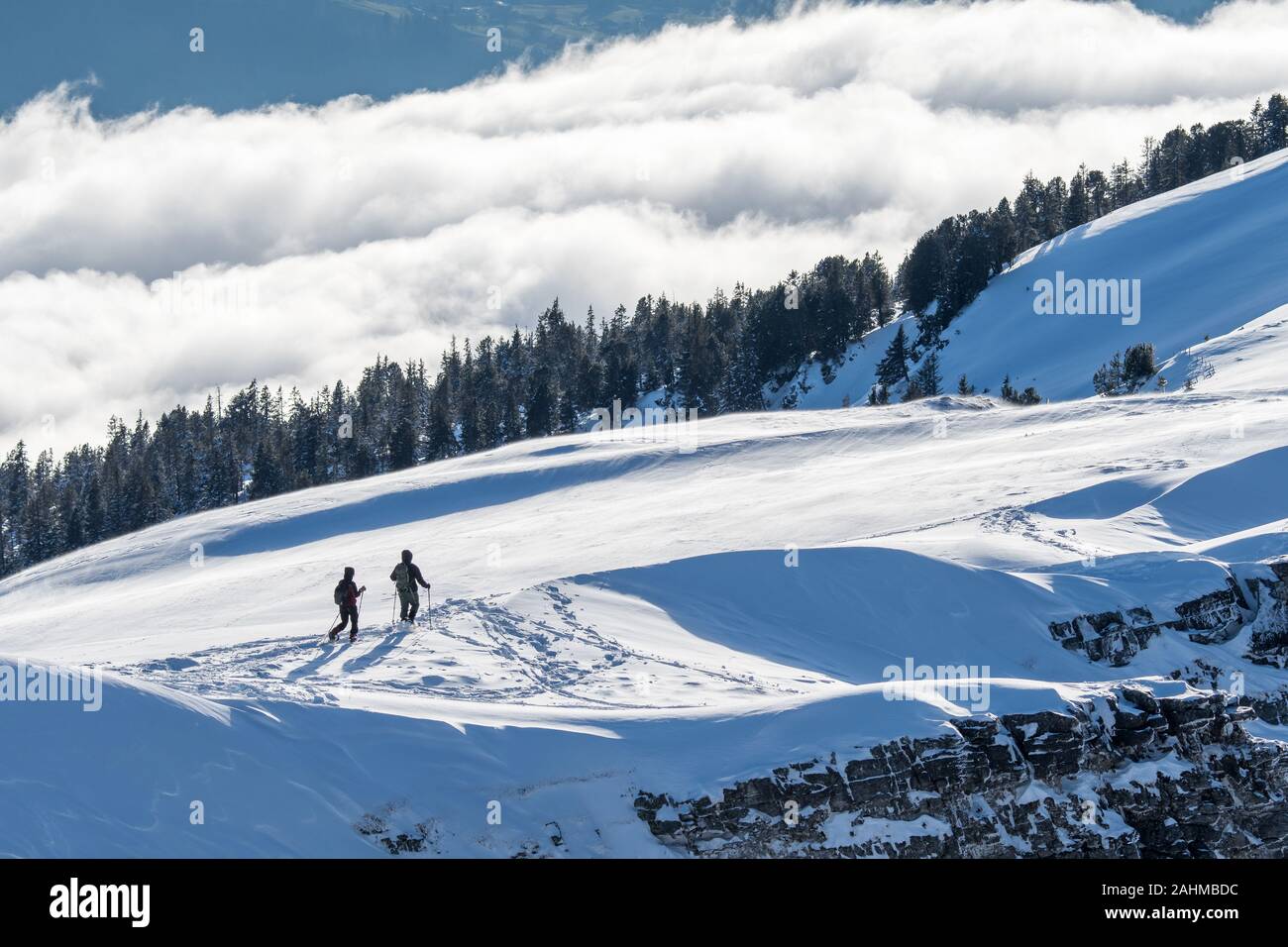 Coppia di escursionisti con racchette da neve davanti a un mare di nebbia Foto Stock