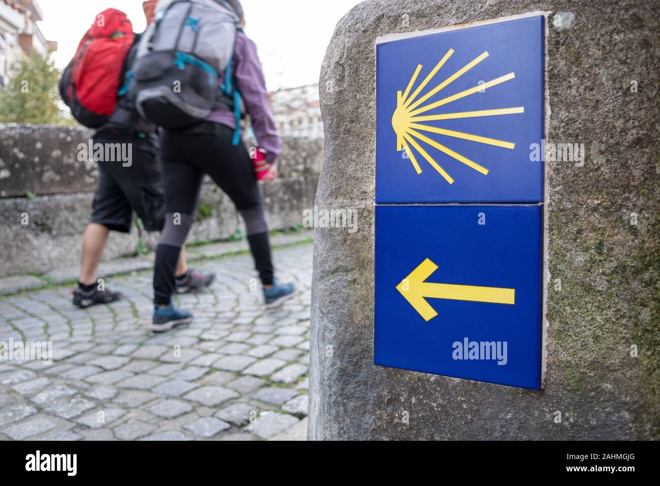 Modo di San Giacomo segno e pellegrini non focalizzato in background. Scaloppina giallo segno pellegrinaggio a Santiago de Compostela Foto Stock