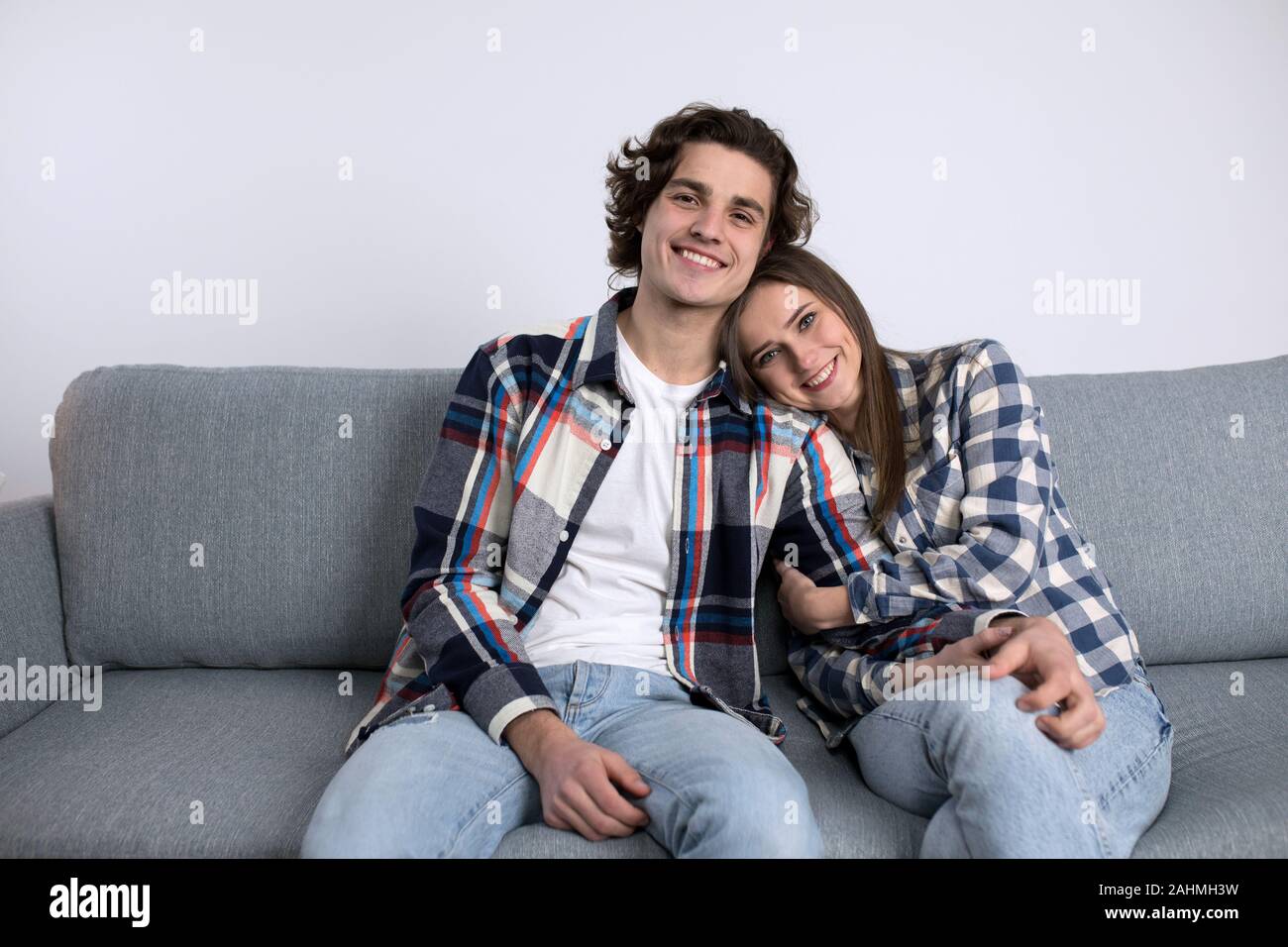Rilassata giovane coppia sorridente mentre posa sul divano. Foto Stock