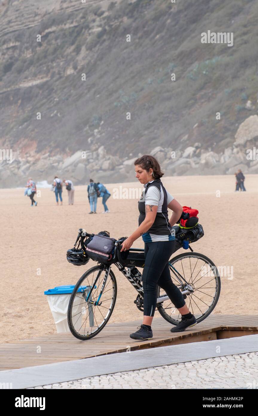 Turista femminile sulla gita in bicicletta con la sua bicicletta sulla spiaggia di nazare, Portogallo Foto Stock
