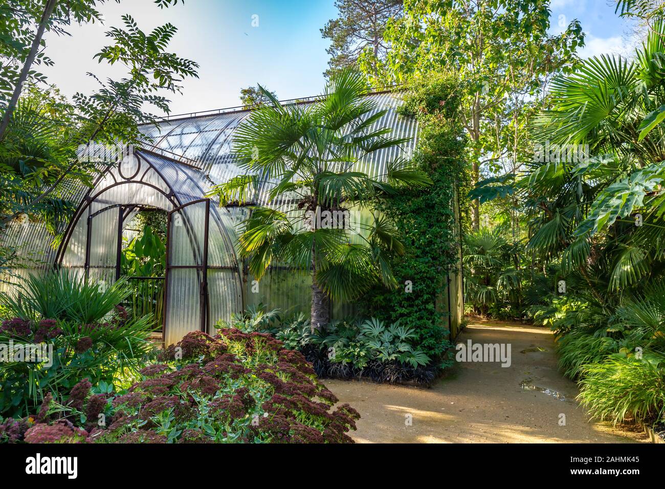 Bellissimo tondo sagomato casa verde da acciaio arrugginito e lastre ondulate in un giardino circondato da alberi Foto Stock