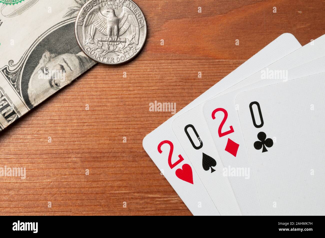 Anno nuovo concetto: quattro carta da gioco con valori formando il numero 2020 sul tavolo di legno con un dollaro e un quarto di dollaro Foto Stock