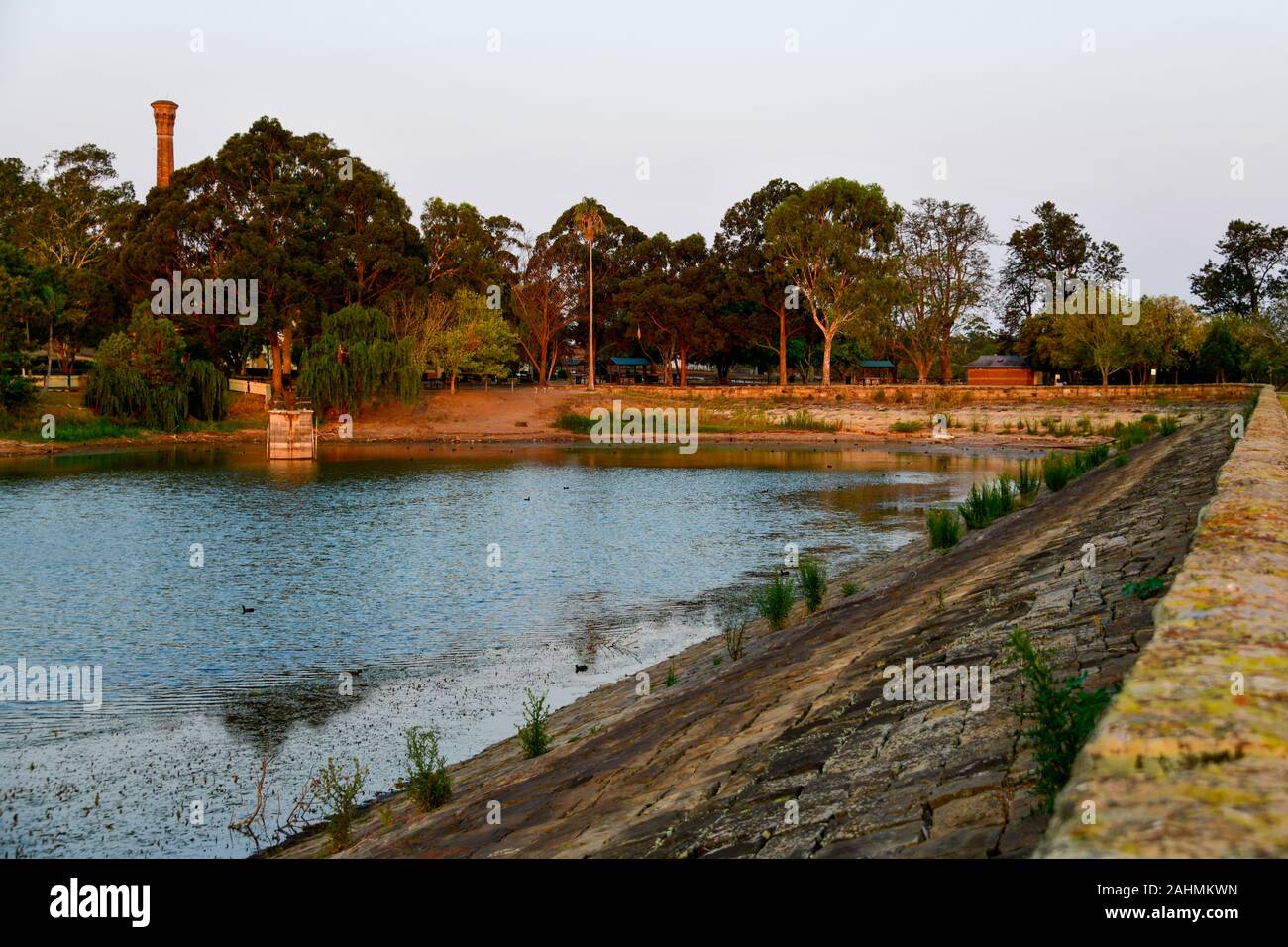 Bella colorato tramonto sul lago e la parete di pietra arenaria, XIX secolo nel patrimonio culturale ex sito industriale Walka opere idriche, Maitland, Australia Foto Stock