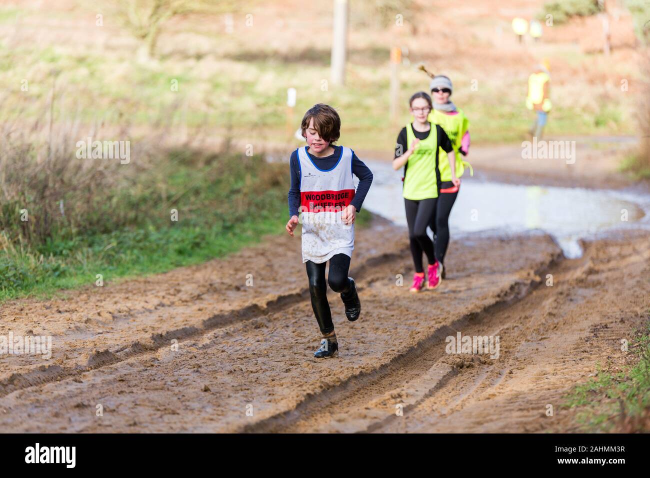 Sutton, Suffolk, Regno Unito 15 Dicembre 2019: Un juniors sotto 18 cross country gara di corsa attraverso una campagna fangose corso Foto Stock