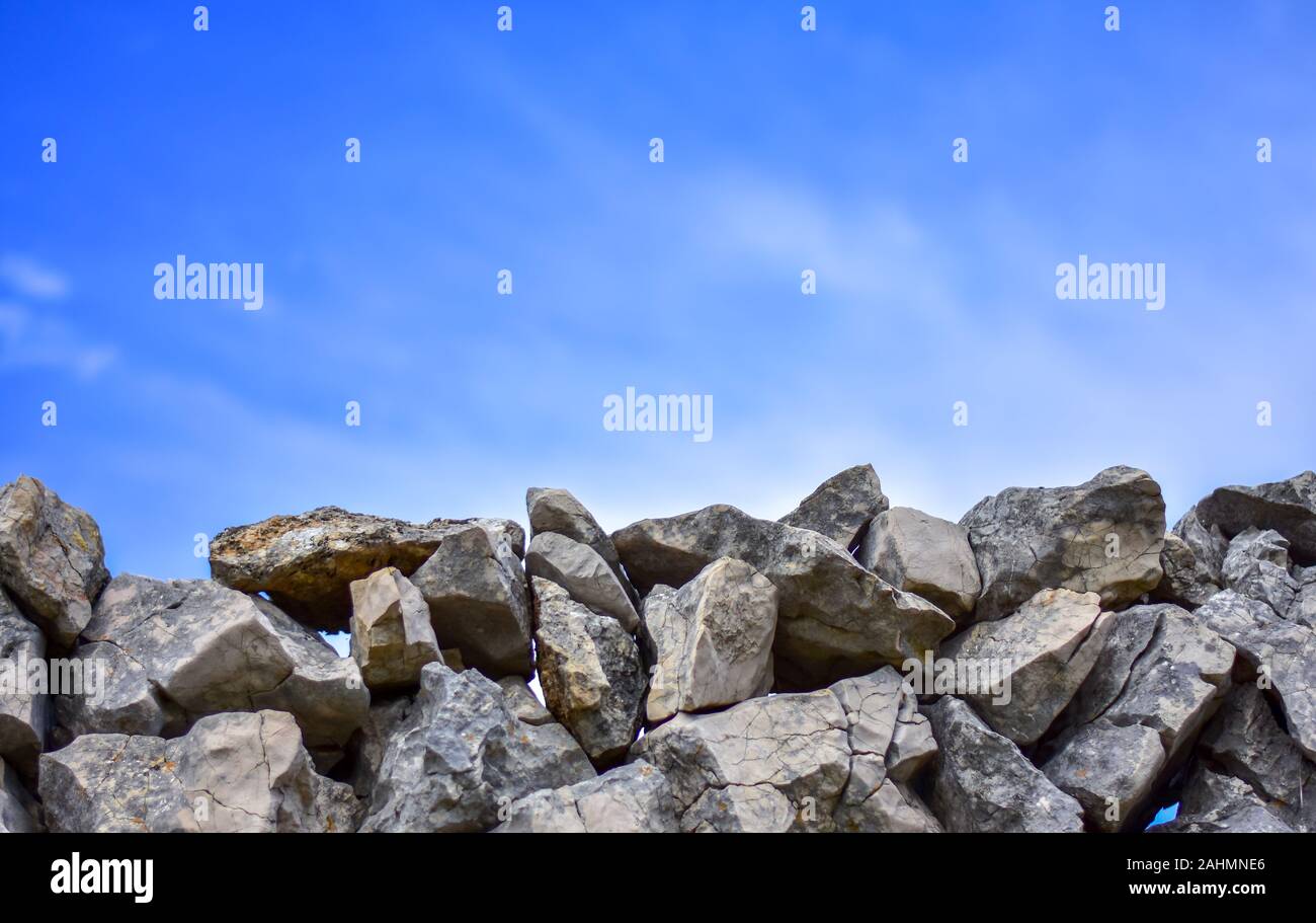 Muro di pietra. Fatti a mano, recinzione. Muro di pietra con un cielo blu con nuvole. Con un sacco di spazio copia. La foto in orizzontale. Foto Stock