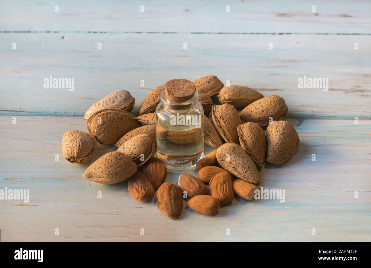Olio di mandorla con mandorle naturale, su un bianco tavola di legno. Foto Stock