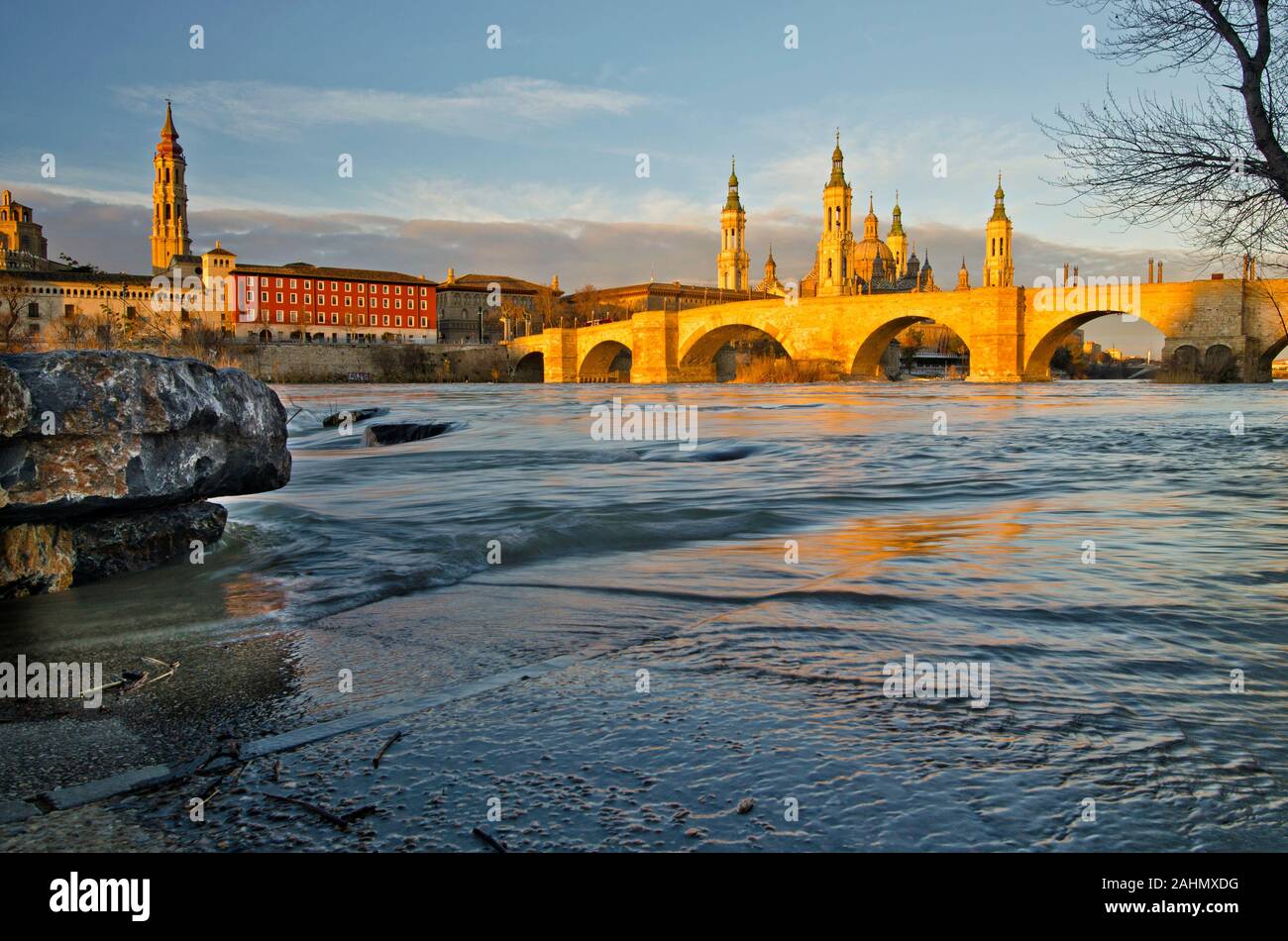 Il vecchio ponte in pietra attraverso il fiume Ebro a Saragozza in mattina presto le luci dell'alba, Basilica Cattedrale della Madonna del Pilastro è dietro. Cath Foto Stock