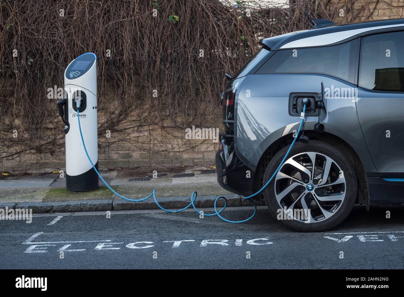 Un'auto che utilizza un vano di ricarica per auto elettriche su strada. Misure volte a migliorare la qualità dell'aria e a ridurre l'inquinamento. Foto Stock