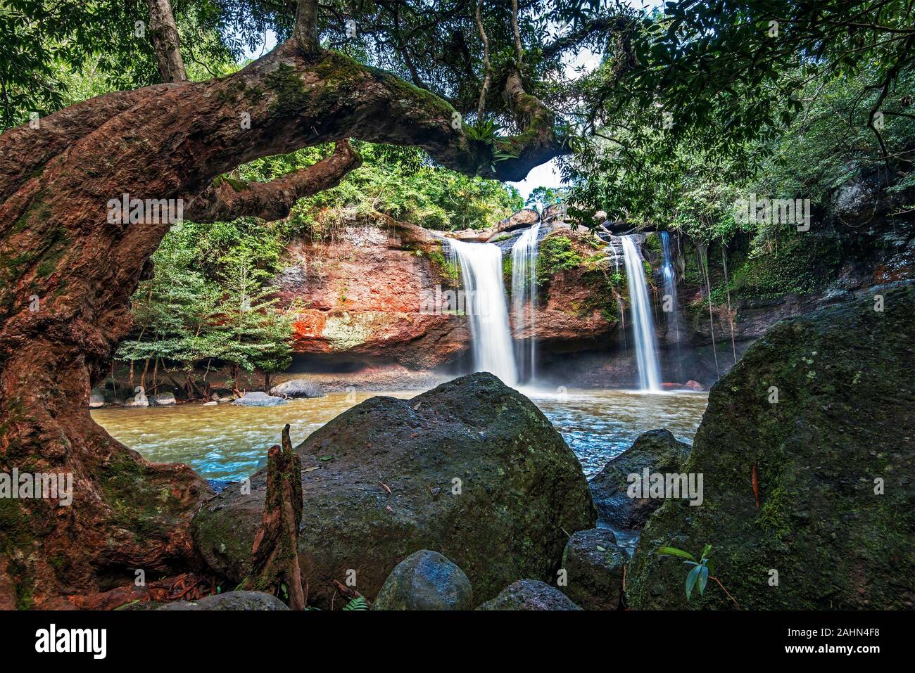 Vista in Haew Suwat cascata nel Parco Nazionale di Khao Yai in Thailandia. Tronco di albero e pietre sono in primo piano Foto Stock