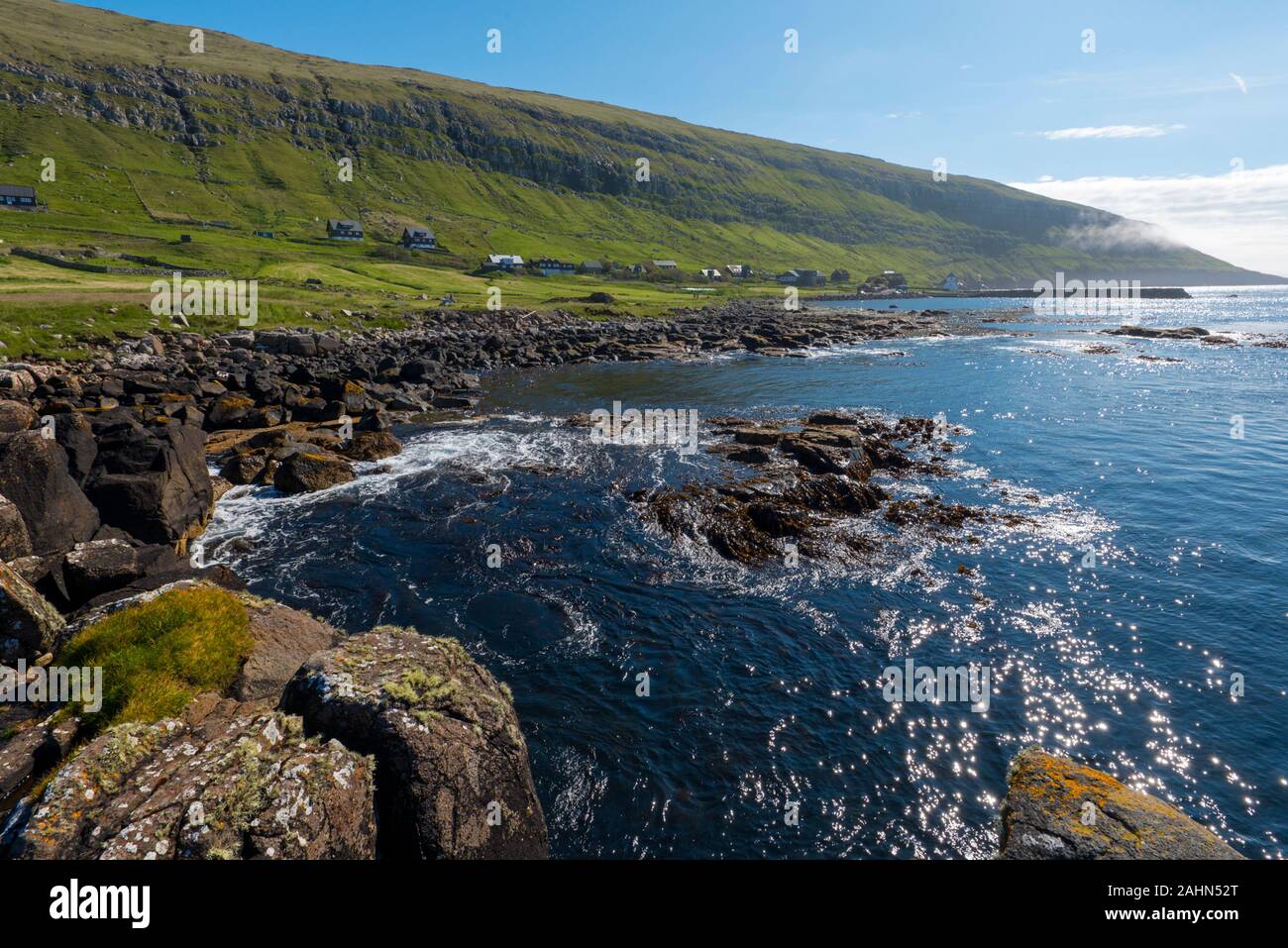 Vista sul villaggio Kirkjubour dal rocky ocean costo, Faroese isola di Streymoy Foto Stock