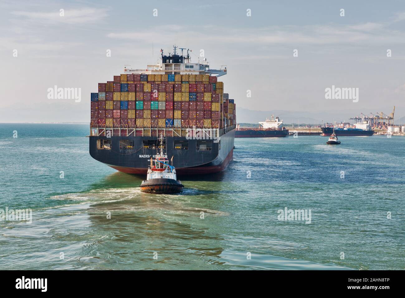 LIVORNO, Italia - Luglio 23, 2019: rimorchiatori e un enorme contenitore di carico nave Maersk Kowloon entrando in porto. Maersk Line è un mondo più grande internazionale danese c Foto Stock
