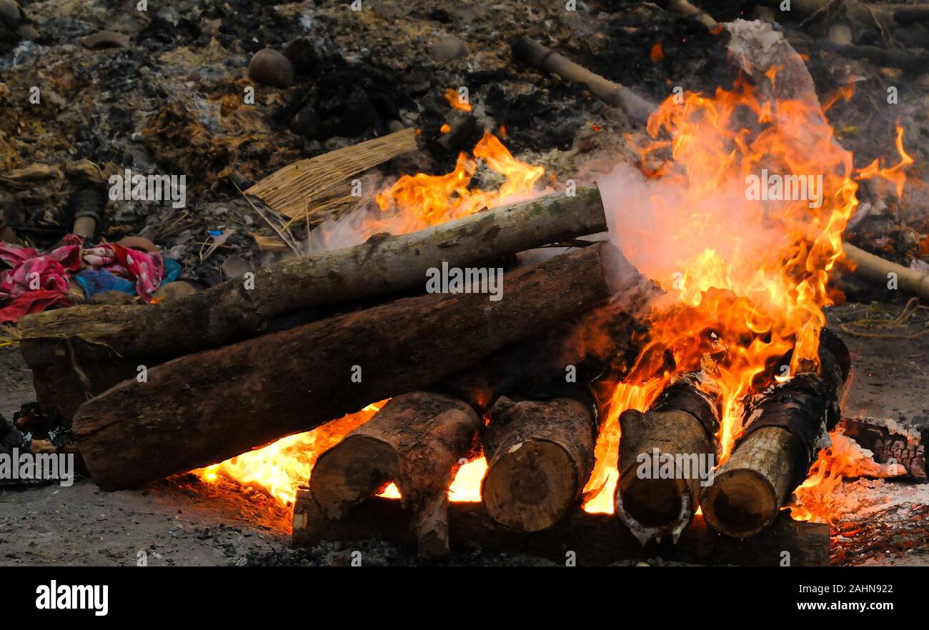 Il corpo di una persona indù è di essere cremato nel modo tradizionale e,circondato da simili pire il calore intenso,il fumo e gli odori sono schiaccianti. Foto Stock