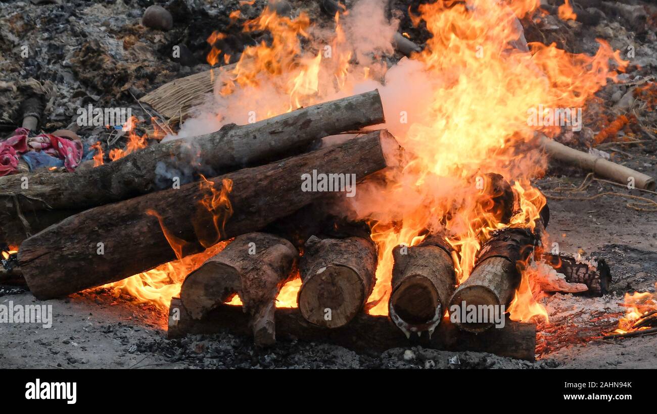Il corpo di una persona indù è di essere cremato nel modo tradizionale e,circondato da simili pire il calore intenso,il fumo e gli odori sono schiaccianti. Foto Stock