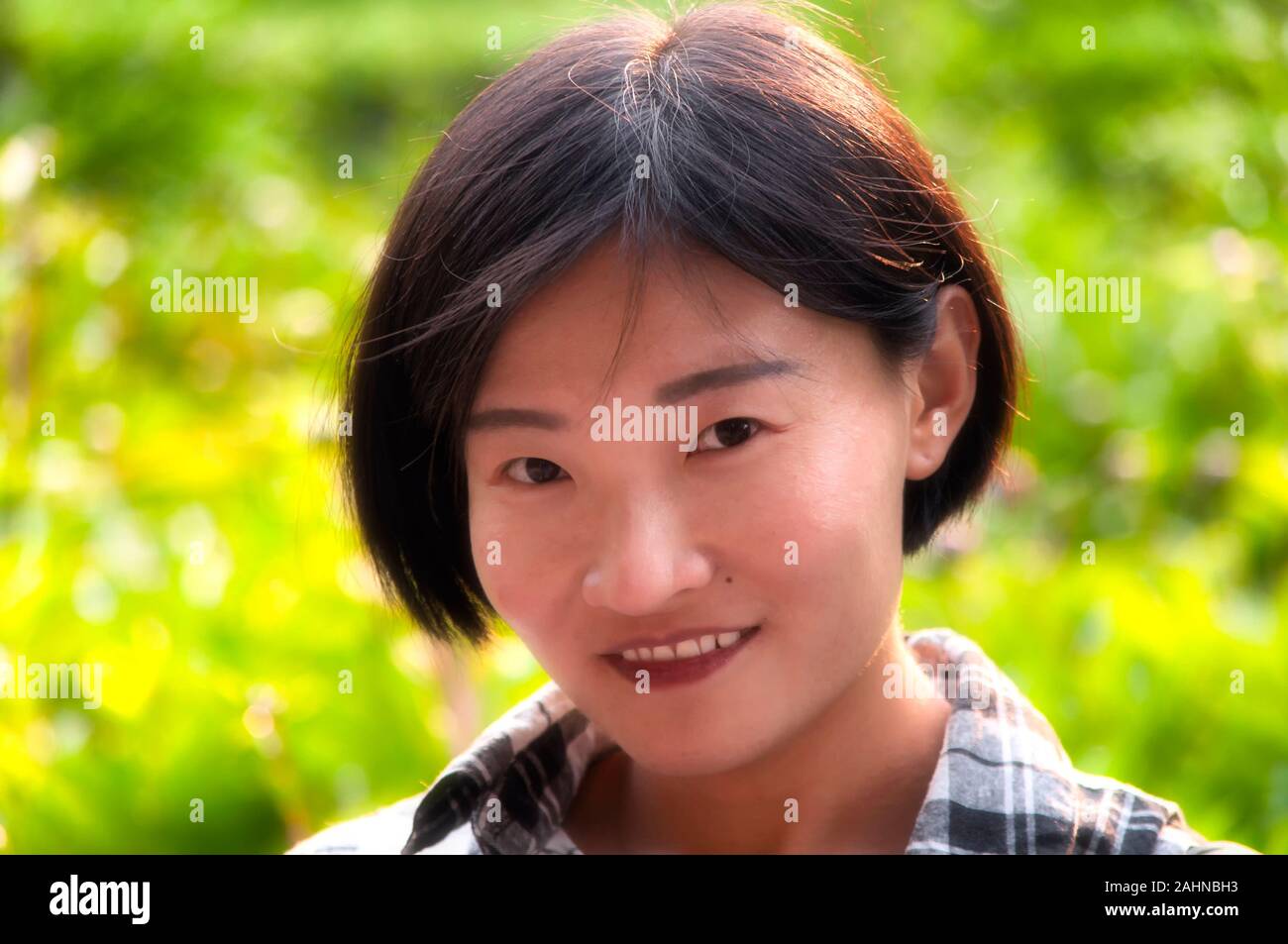 Un felice donna cinese che indossa un bianco e nero plaid shirt sopra Parco Jingshan a Beijing in Cina in una giornata di sole in soft focus. Foto Stock Un felice donna cinese che indossa un bianco e nero plaid shirt sopra Parco Jingshan a Beijing in Cina in una giornata di sole in soft focus. Foto Stock