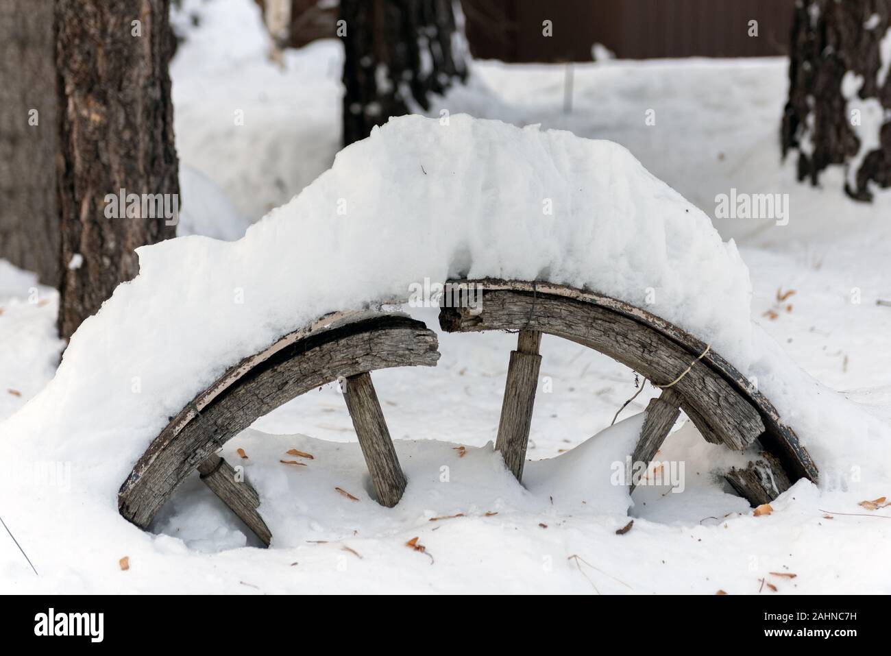 Vintage decorativi antichi ruota di carro con broken spoke coperto di neve dopo la tempesta di neve passa attraverso la zona rurale di Wrightwood in Califor Foto Stock