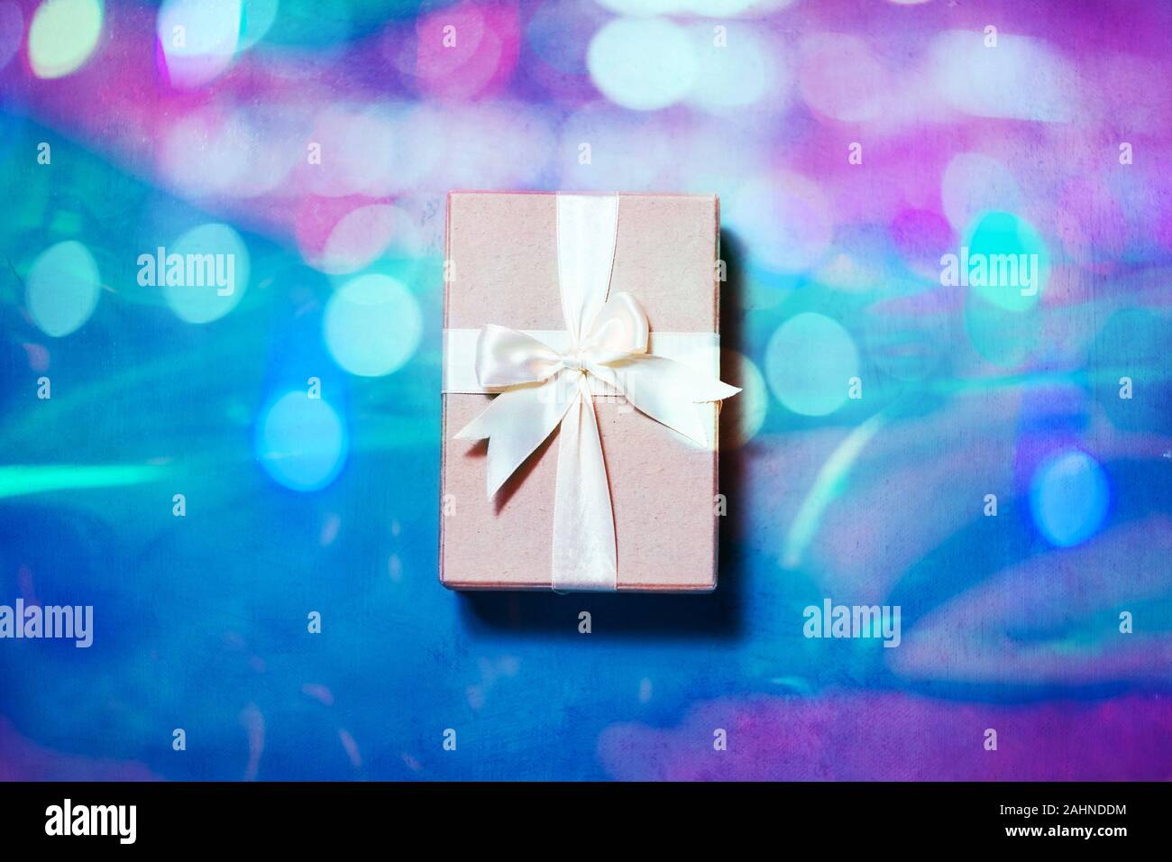 Confezione regalo con nastro su sfondo olografica. Minima laici piana in una luce al neon Foto Stock