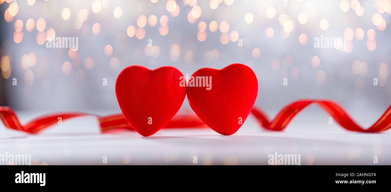 Il giorno di San Valentino card. Due cuori con nastri rossi in background sul tavolo bianco Foto Stock
