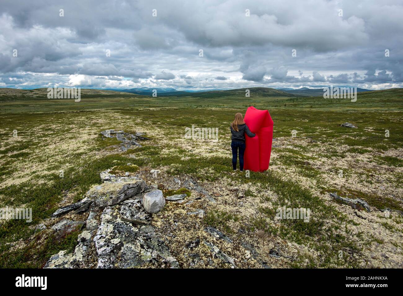 Il paesaggio del deserto di Valle Remdalen nelle highlands norvegese di Oppland. Giovane donna con aria rosso lettino posizionato da dietro è al primo piano Foto Stock