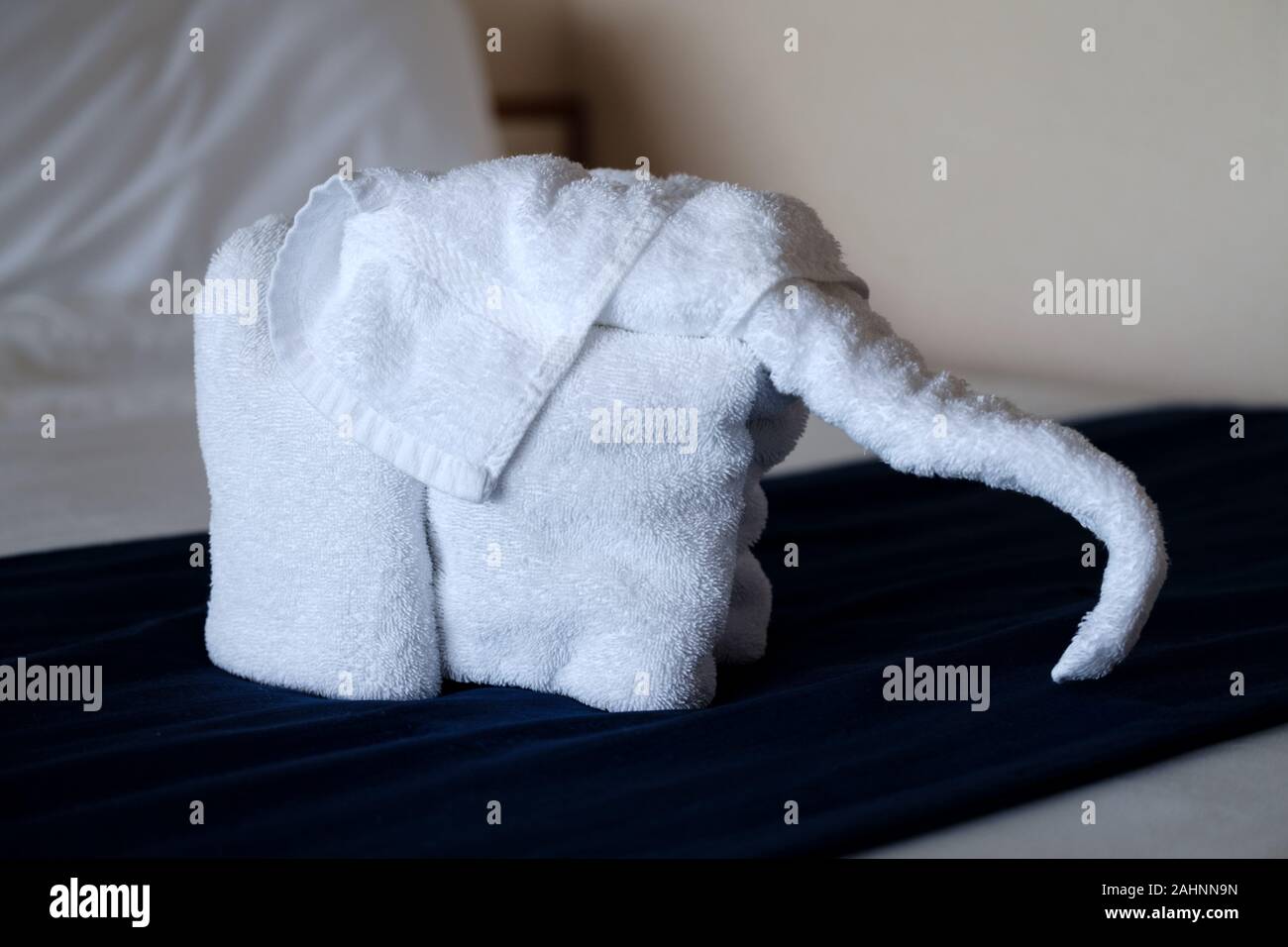 Un animale dell'origami dell'asciugamano fatto dagli asciugamani della camera dell'hotel nella forma di un elefante. È stato lasciato sul letto degli ospiti dal servizio in camera Foto Stock