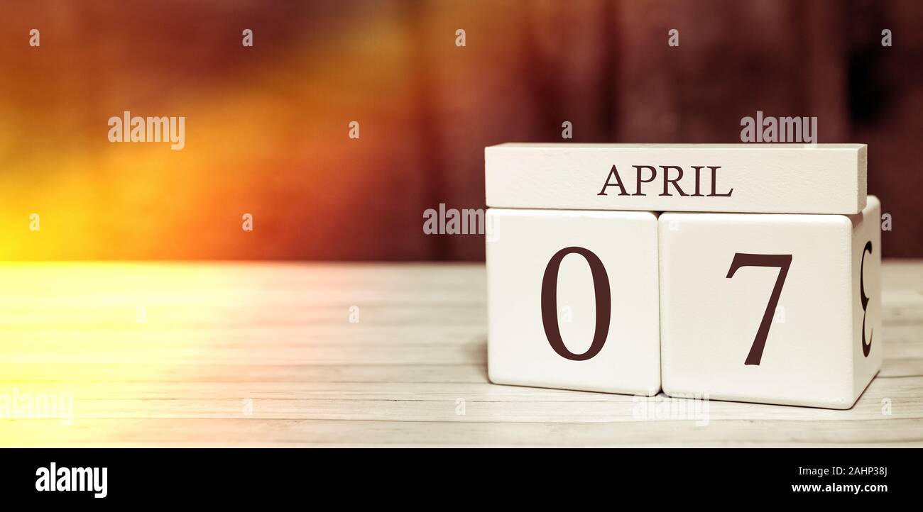 Promemoria del calendario il concetto di evento. Cubi di legno con numeri e mese il 7 aprile con la luce del sole. Foto Stock