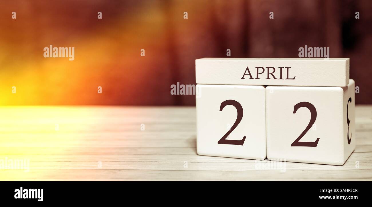 Promemoria del calendario il concetto di evento. Cubi di legno con numeri e mese del 22 aprile con la luce del sole. Foto Stock