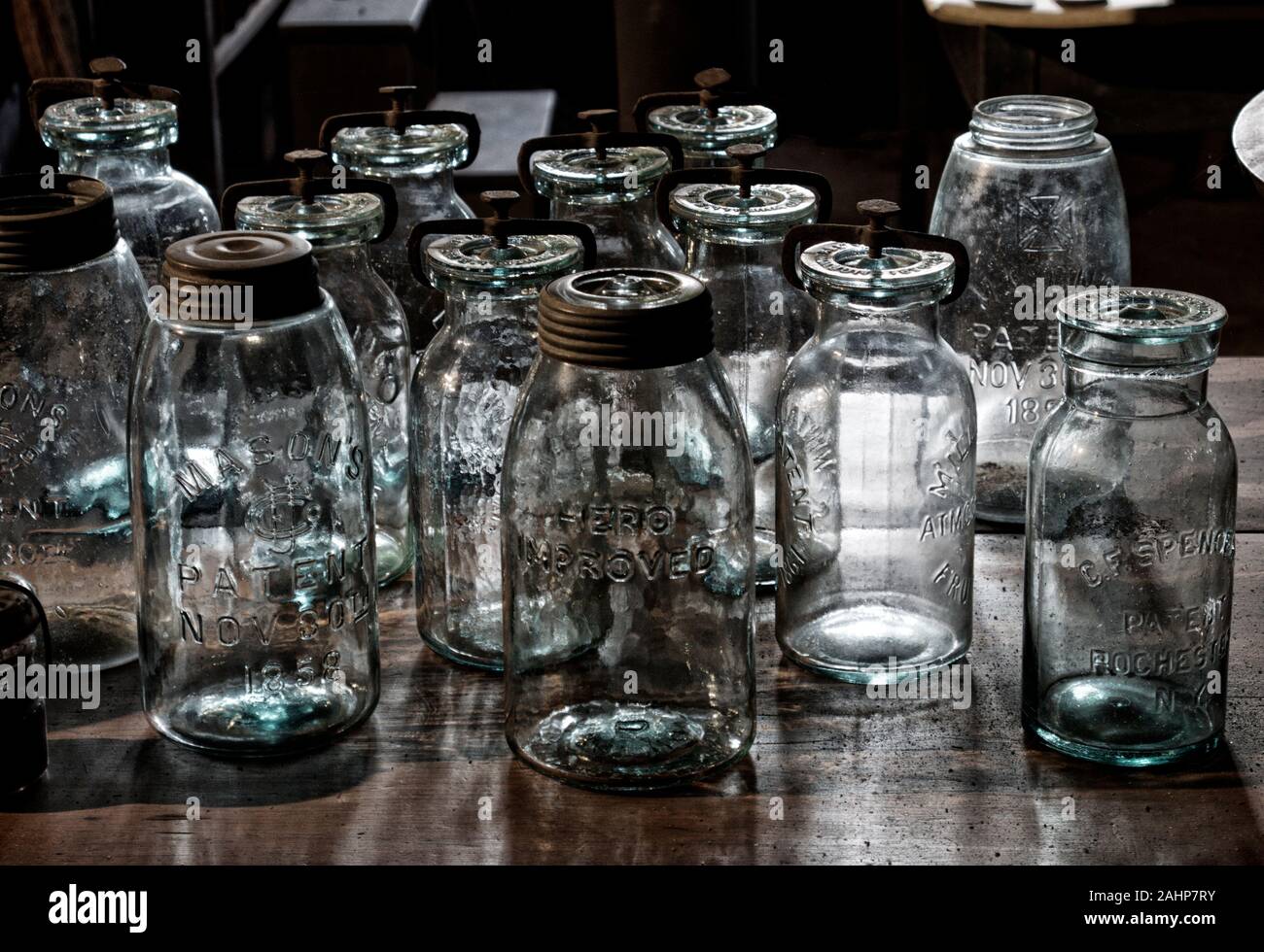 La luce del sole si riflette attraverso un gruppo di vasetti in vetro d'epoca. Giochi di luce artistica, ombre e riflessi su vetri antichi. Foto Stock