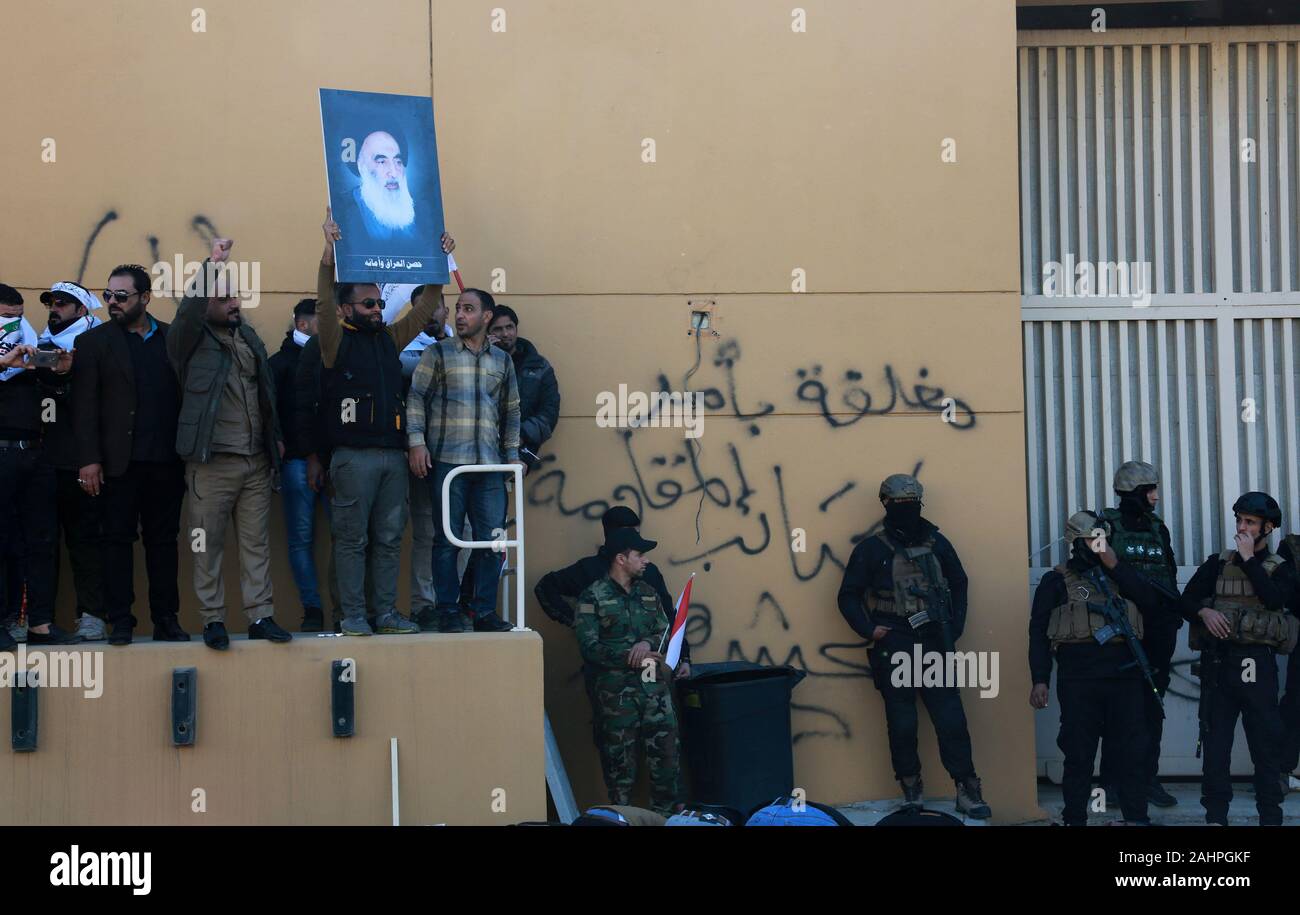 Baghdad in Iraq. 31 Dic, 2019. Un iracheno sostenitore di hashing al-Shaabi rete militare solleva un'immagine dell'Iraq la cima del chierico sciita il grande ayatollah Ali Sistani durante un rally di fronte theU.S. Ambasciata, a Baghdad, Iraq, Martedì, Dicembre. 31, 2019. Decine di angry sciita irachena i sostenitori della milizia si rompe in Stati Uniti Composto di ambasciata a Baghdad il martedì dopo lo sfondamento di una porta principale e l'impostazione di fuoco ad un area di ricevimento. Foto di Humam Mohamed /UPI Credito: UPI/Alamy Live News Foto Stock