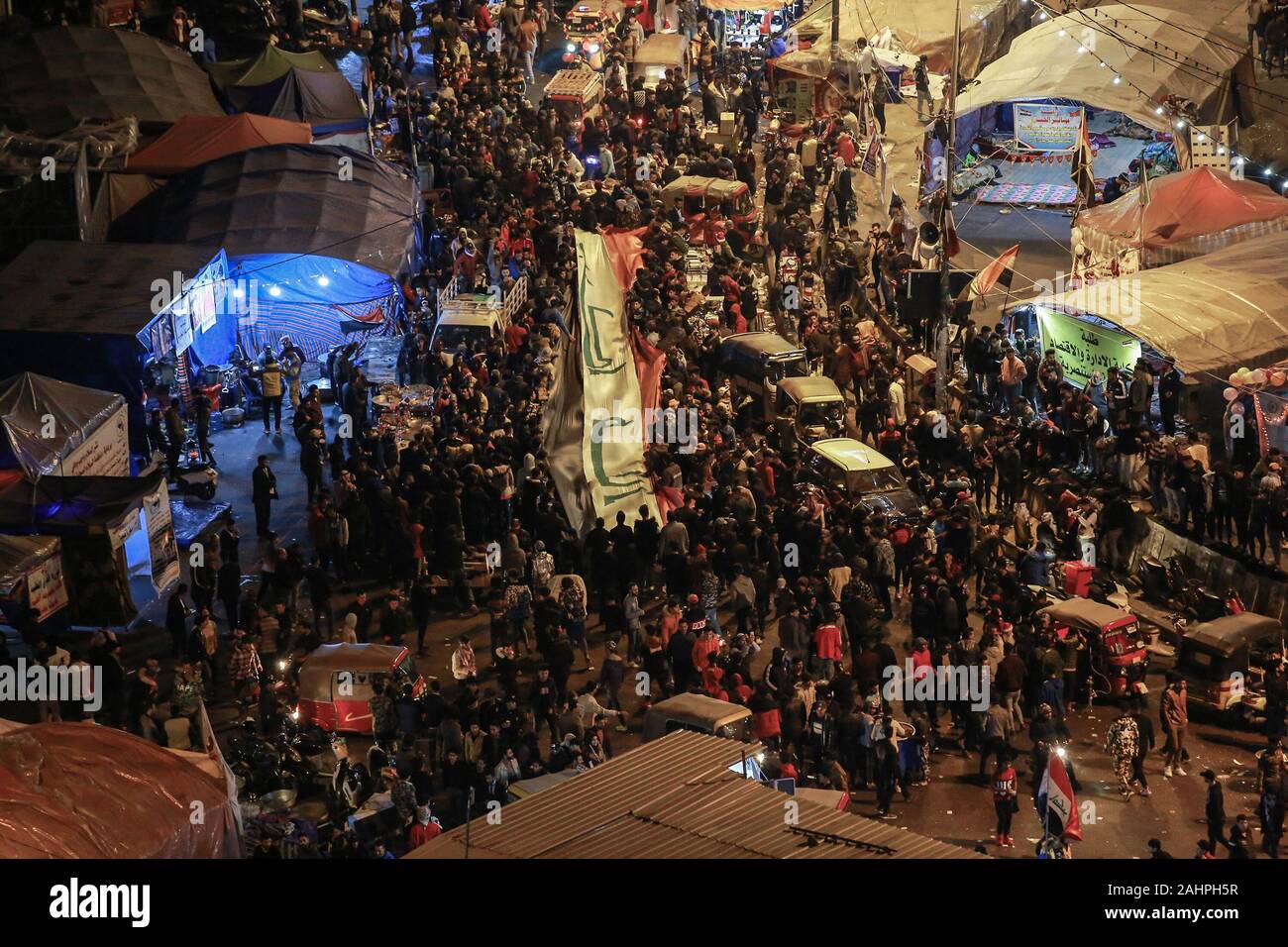 Baghdad in Iraq. 31 Dic, 2019. Le persone in possesso di una grande bandiera irachena che si ritrovano nella Piazza Tahrir per celebrare il 2020 Capodanno. Credito: Ameer Al Mohmmedaw/dpa/Alamy Live News Foto Stock