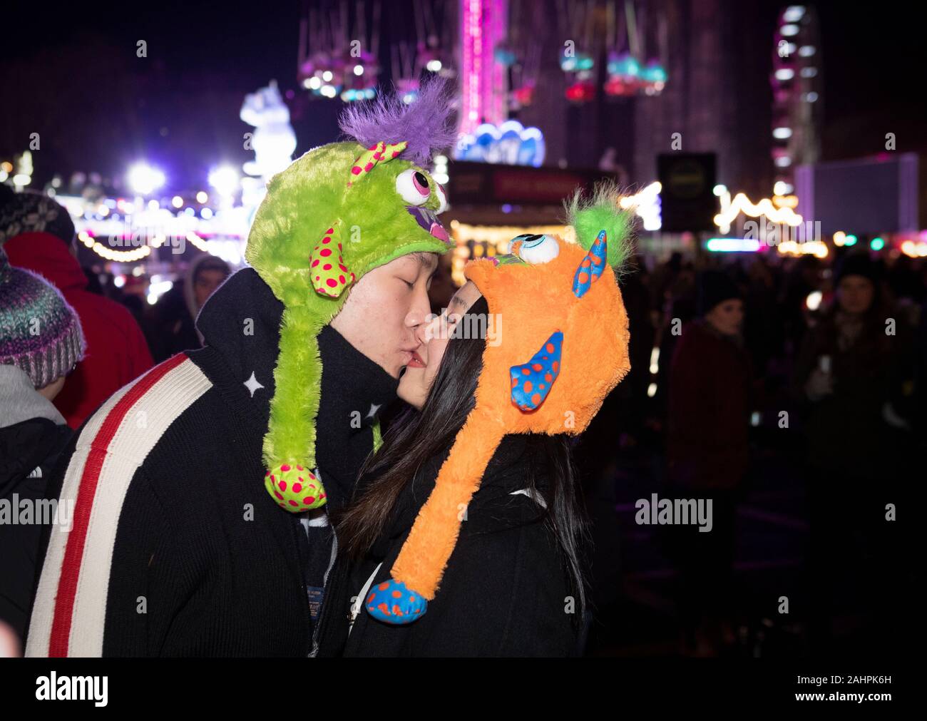 Festaioli dalla Cina condividono un bacio durante la festa di strada su Princes Street durante l'Hogmanay festeggiamenti di Capodanno a Edimburgo. Foto Stock