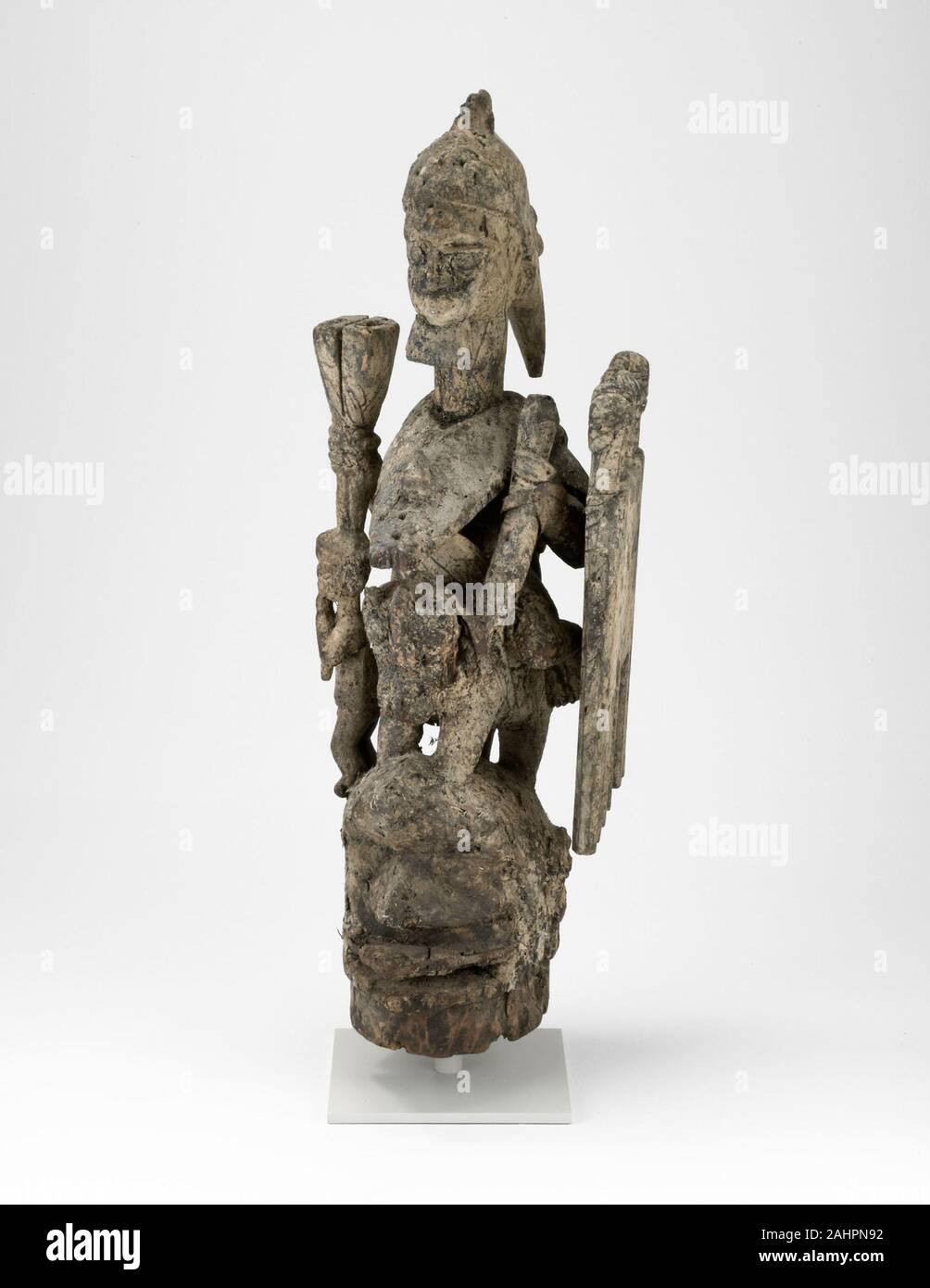 Yoruba. Copricapo (Jagún Jagún). 1834-1900. La Nigeria. Legno, ferro, chiodi, fibre e materiali sacrificali questo imponente acconciatura scultorea sarebbe stato indossato in maschera onorando Ogun, Yoruba dio di ferro, warfare e tecnologia. Si è anche parte di un santuario dove le offerte di filati sono stati applicati alla sua superficie. Ogun è raffigurato come un guerriero a cavallo che porta uno scudo con quattro teste umane, eventualmente ucciso i nemici. La figura più piccola riproduzione di un flauto rappresenta Eshu, il messaggero divino e dio del destino umano. Foto Stock