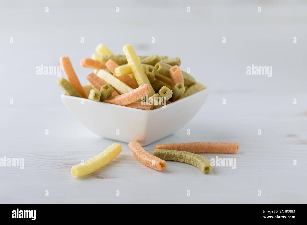 Una vista ravvicinata di un piatto bianco pieno di puff stick forma snack pronti per mangiare. Foto Stock