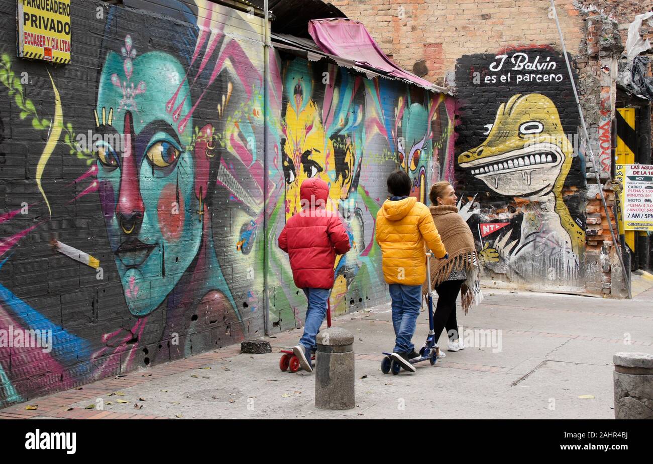 La donna e i bambini passando la street art e graffiti dipinti su esterno di edifici in Candelaria distretto di Bogotà, Colombia Foto Stock