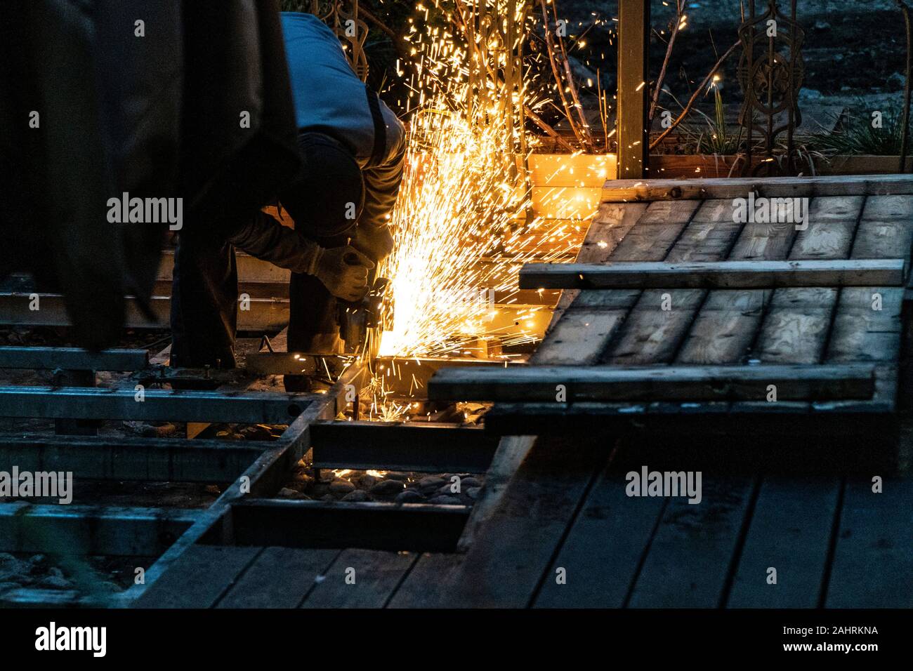 Un lavoratore edile utilizzando una smerigliatrice angolare producendo un sacco di scintille Foto Stock