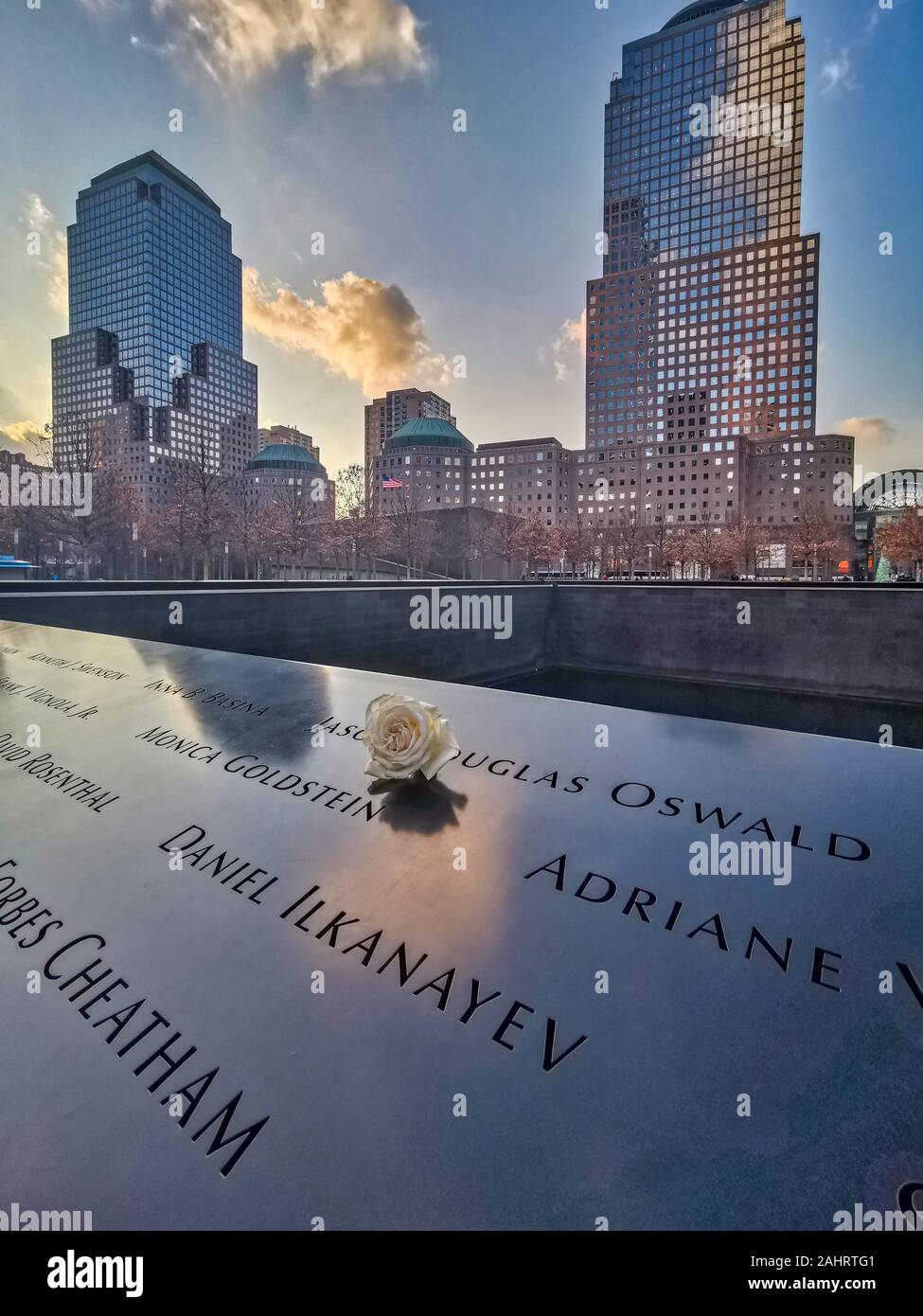 New York , USA-dicembre 14,2019: 9/11 memorial con fiore bianco in primo piano e grattacieli in background Foto Stock