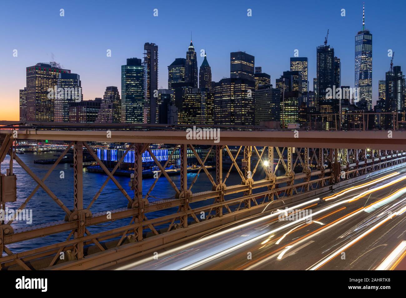 Skyline di New York dal ponte di Brooklyn a esposizione notturna riprese con percorsi leggeri da auto in movimento Foto Stock
