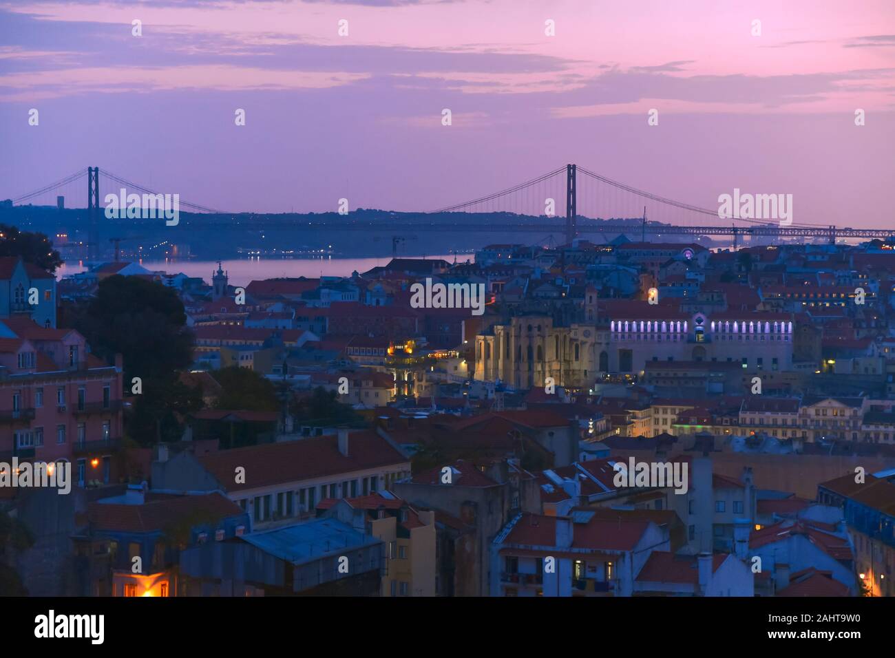 Lisbona vista panoramica. Le pareti colorate degli edifici di Lisbona, con tetti di colore arancione e il venticinquesimo del ponte di aprile in background, al tramonto. Viaggiare Foto Stock