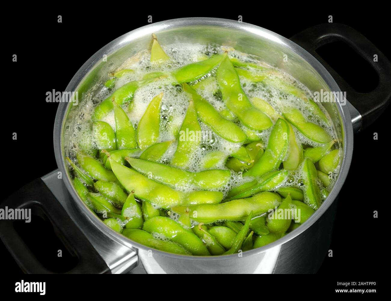 Edamame, verde fagioli di soia, maodou, con punto di ebollizione in acqua salata in una pentola di metallo. I fagioli di soia, Glycine max, un legume che bis ricca di proteine. Foto Stock