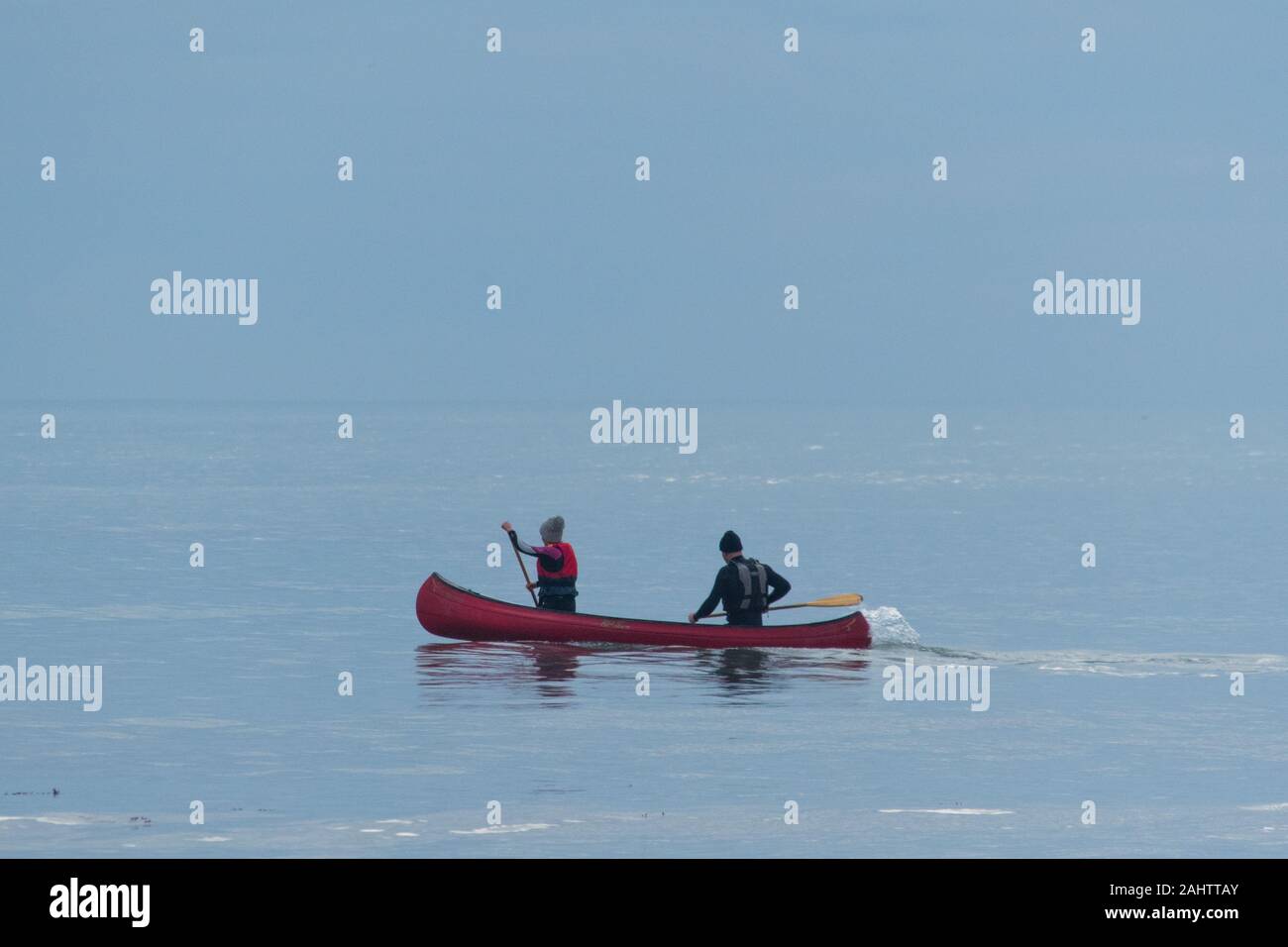 Marazion, Cornwall, Regno Unito. Il 1 gennaio 2020. Regno Unito Meteo. Cieli grigi a partire per dare modo al blu su una molto lieve e calma giorno a Marazion. Questo giovane erano fuori sul loro canoe, con il mare e il cielo quasi la miscelazione in uno. Simon credito Maycock /Alamy Live News. Foto Stock