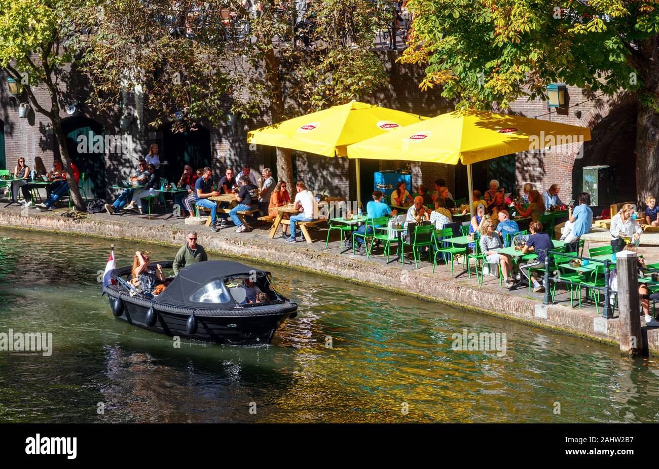 Barca a Oudegracht (vecchio canale) e turisti che si godono le condizioni meteorologiche a terrazze su pontili della Stadhuisbrug. Utrecht, Paesi Bassi. Foto Stock